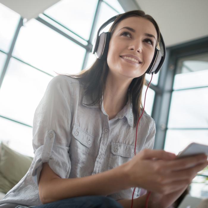 woman with headphones listening to audio from her cellphone