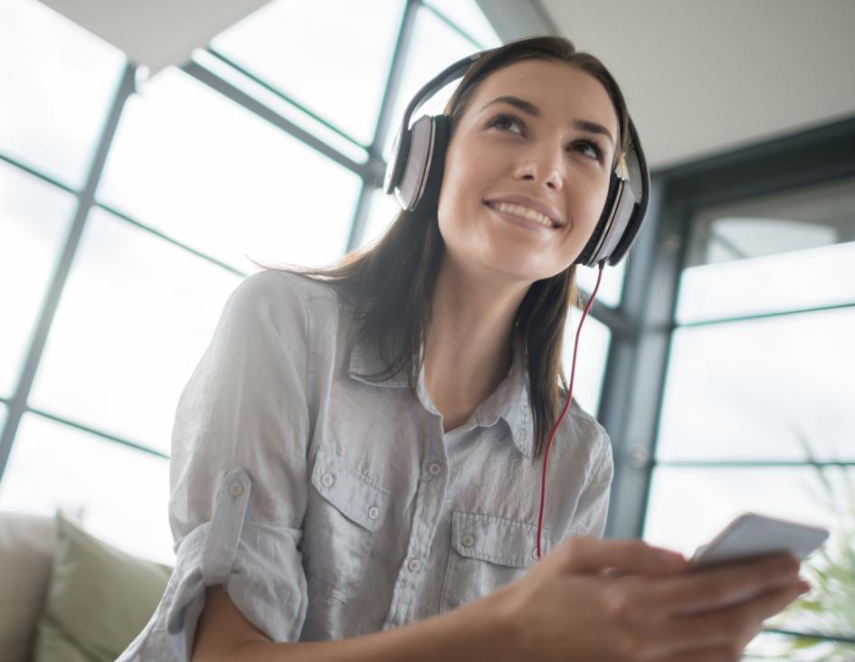 woman with headphones listening to audio from her cellphone