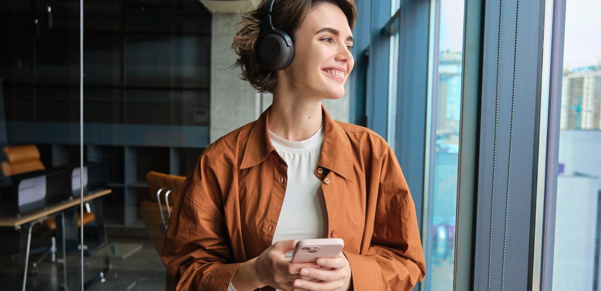 women wearing headphones holding her phone