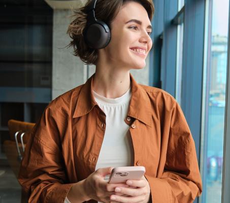 women wearing headphones holding her phone